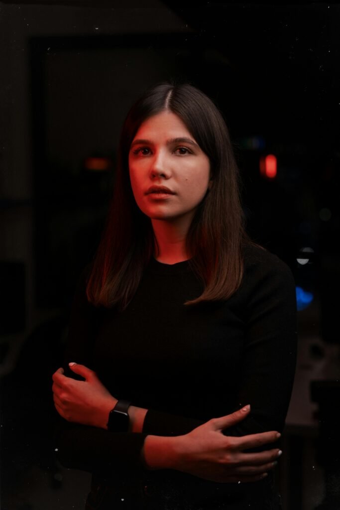 Captivating portrait of a woman with crossed arms in dramatic red lighting indoors.
